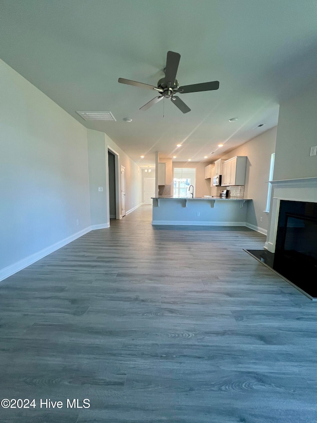 unfurnished living room featuring ceiling fan and hardwood / wood-style flooring