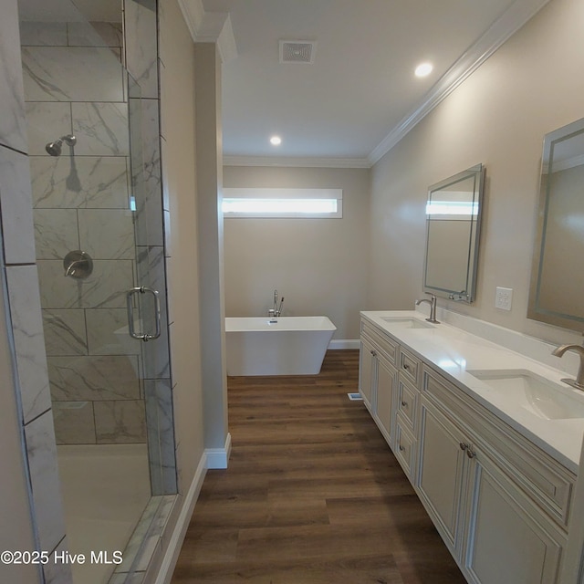 bathroom with visible vents, wood finished floors, a sink, and ornamental molding