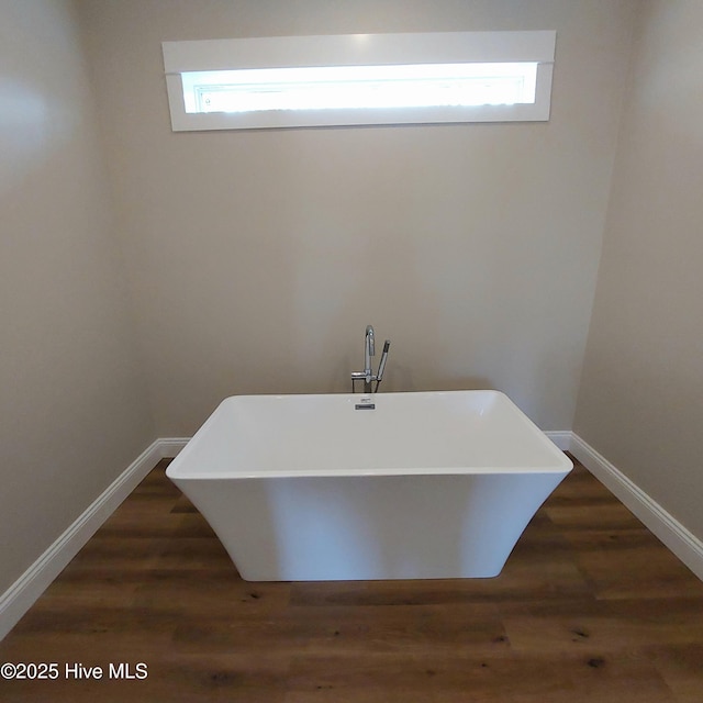 full bath featuring a freestanding bath, plenty of natural light, and wood finished floors