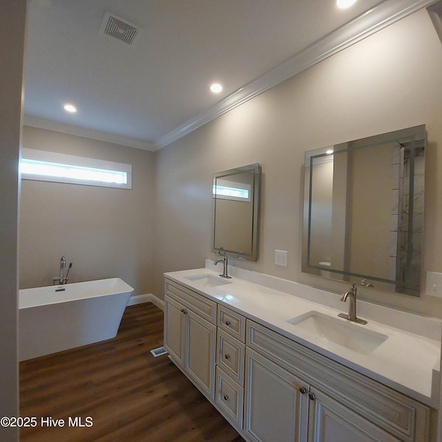 full bath with ornamental molding, visible vents, a sink, and wood finished floors