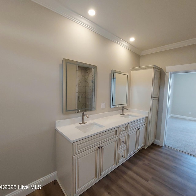 bathroom featuring wood finished floors, ornamental molding, a sink, and baseboards