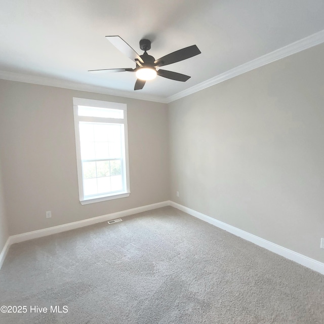 carpeted spare room with a ceiling fan, visible vents, ornamental molding, and baseboards