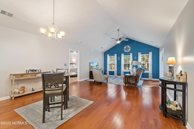 dining area with wood-type flooring, ceiling fan with notable chandelier, and vaulted ceiling