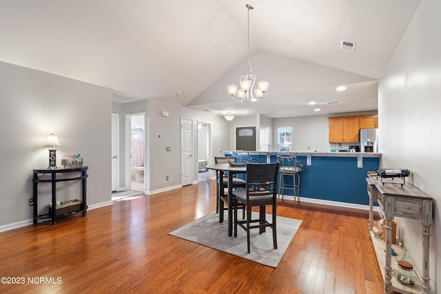 dining space featuring an inviting chandelier, wood-type flooring, and vaulted ceiling