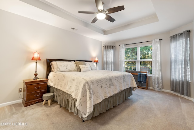 carpeted bedroom with ceiling fan and a raised ceiling