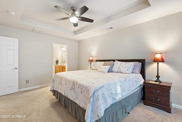 carpeted bedroom featuring ensuite bathroom, ceiling fan, and a tray ceiling