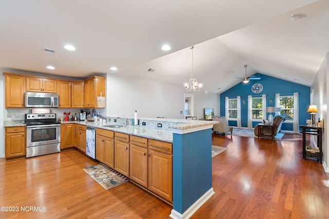 kitchen featuring stainless steel appliances, ceiling fan with notable chandelier, vaulted ceiling, light hardwood / wood-style flooring, and kitchen peninsula