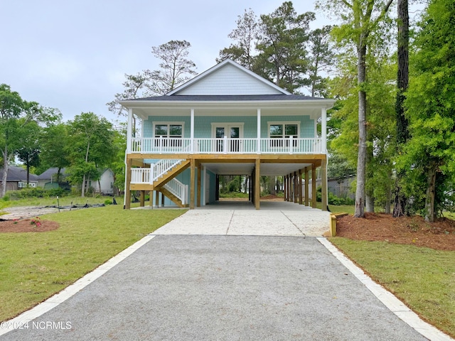 raised beach house with covered porch, a carport, and a front lawn