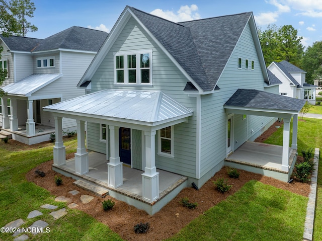 rear view of property featuring a yard and covered porch