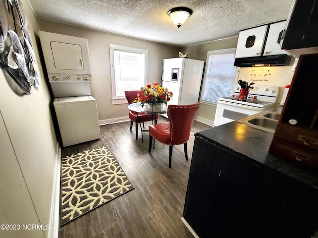 kitchen with a wealth of natural light, white appliances, stacked washer and clothes dryer, and under cabinet range hood