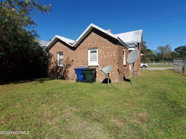 view of home's exterior with a yard, brick siding, and fence