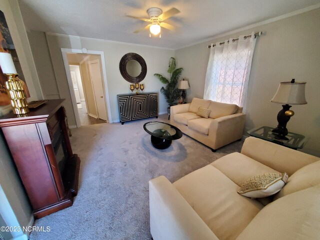 carpeted living room featuring ornamental molding and ceiling fan