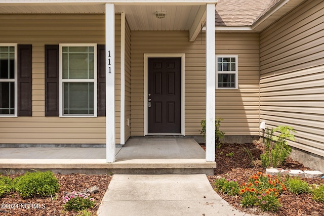 view of exterior entry featuring covered porch