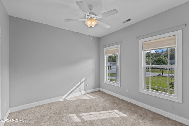 empty room featuring ceiling fan, a wealth of natural light, and carpet floors