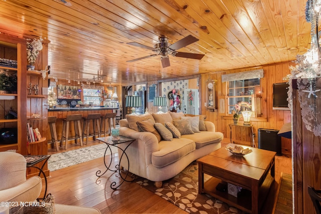 living area featuring bar area, ceiling fan, wood walls, wood ceiling, and wood finished floors