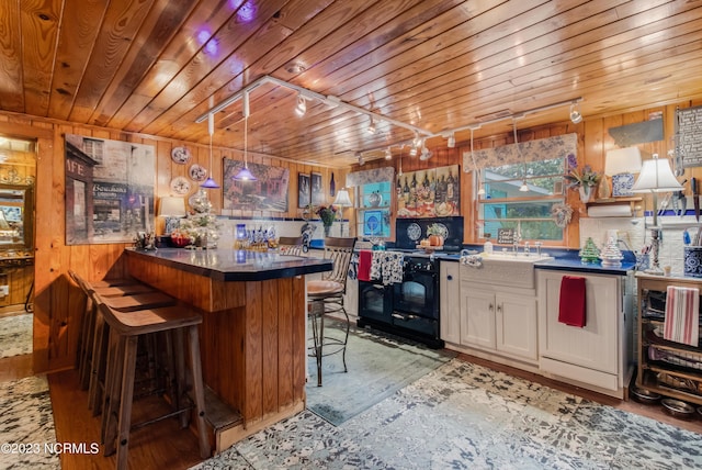 kitchen with dark countertops, wooden walls, white cabinetry, and wood ceiling