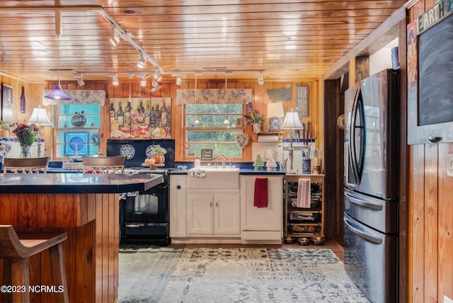 kitchen with dark countertops, stainless steel fridge with ice dispenser, wood ceiling, a kitchen bar, and white cabinets