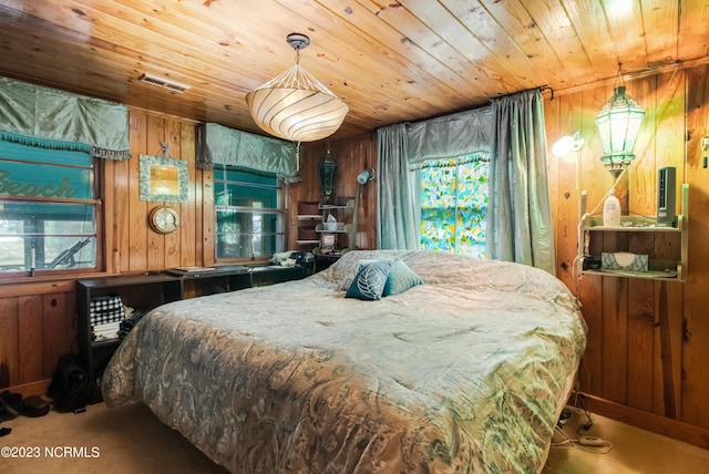 bedroom with visible vents, wood walls, wooden ceiling, and carpet floors