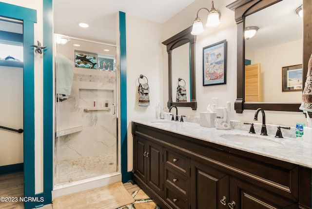 bathroom featuring a sink, a marble finish shower, and double vanity