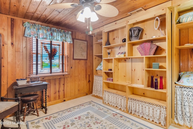 interior space with a ceiling fan, wood ceiling, visible vents, and wood walls