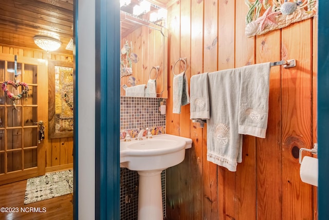 bathroom featuring wood walls, wood finished floors, and a sink