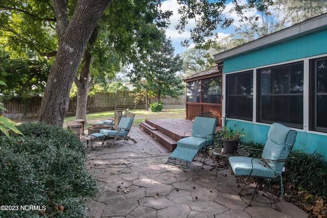 view of patio featuring fence, a deck, and a sunroom