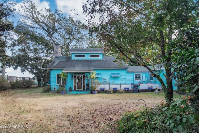 bungalow-style house featuring a shingled roof, a chimney, a front lawn, and fence