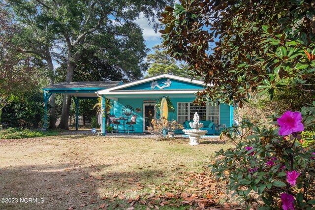 view of front of home featuring a front yard, an attached carport, a porch, and driveway