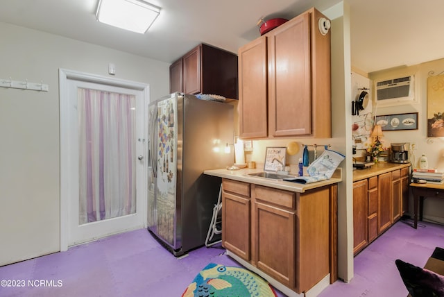 kitchen featuring a wall mounted AC, freestanding refrigerator, a sink, light countertops, and tile patterned floors