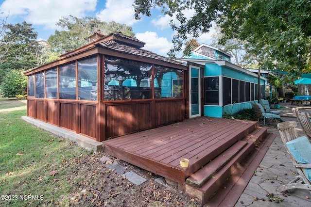 wooden deck with a lawn and a sunroom