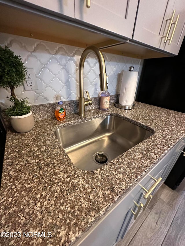 interior details featuring decorative backsplash, dark stone countertops, and sink