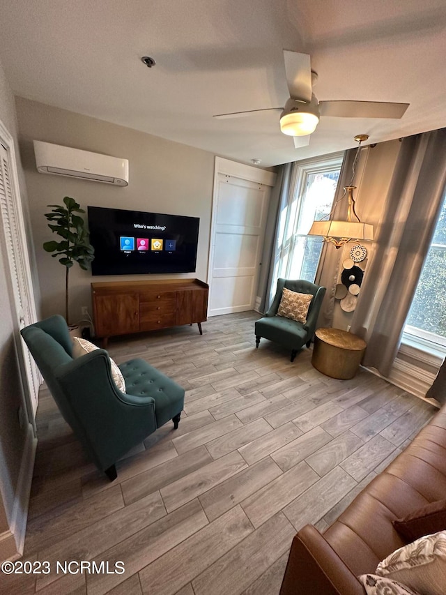 living room with ceiling fan, light hardwood / wood-style floors, and a wall mounted air conditioner