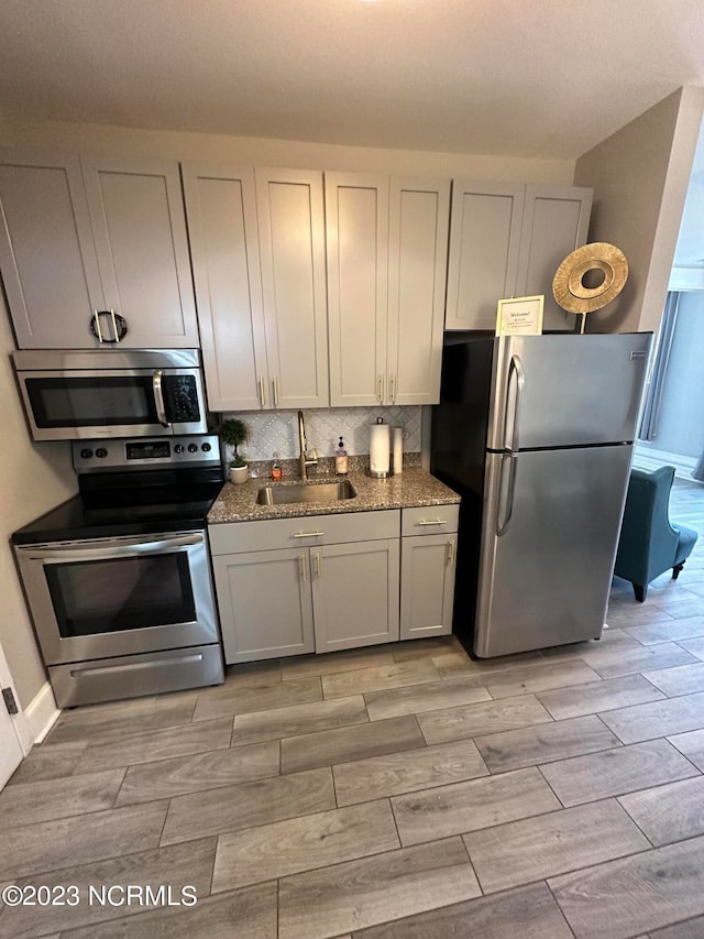 kitchen with light stone counters, appliances with stainless steel finishes, tasteful backsplash, and sink