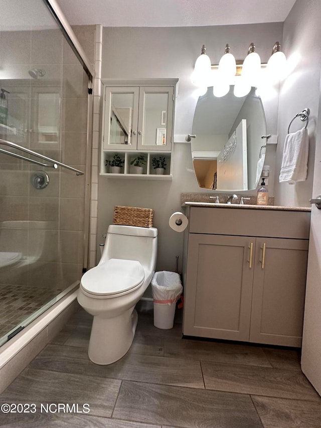 bathroom featuring wood-type flooring, vanity, toilet, and an enclosed shower