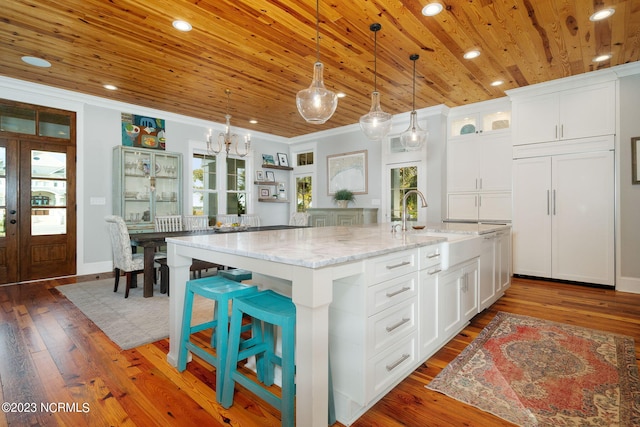 kitchen featuring white cabinets, light stone counters, decorative light fixtures, and dark hardwood / wood-style floors