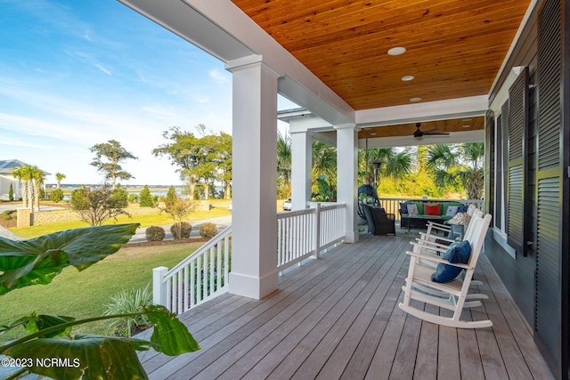 deck featuring covered porch, ceiling fan, and a lawn