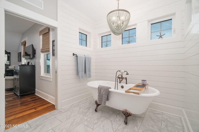 bathroom with a notable chandelier, a washtub, and hardwood / wood-style floors