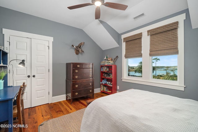 bedroom featuring lofted ceiling, a water view, a closet, ceiling fan, and dark hardwood / wood-style floors