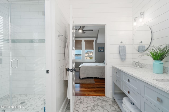 bathroom featuring tile patterned flooring, wooden walls, walk in shower, vanity, and ceiling fan