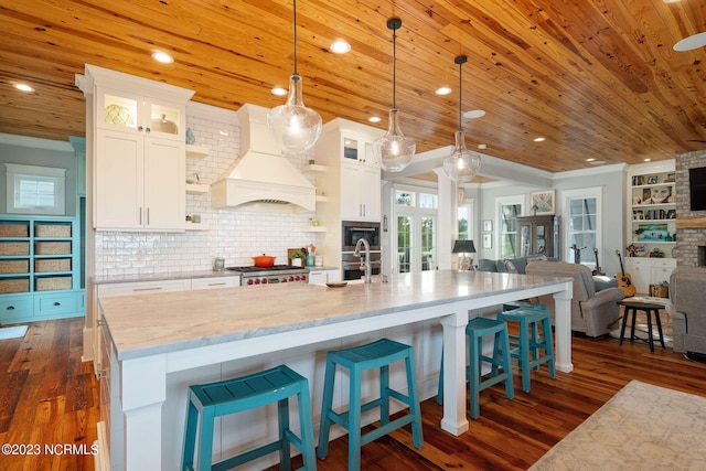 kitchen with white cabinetry, dark hardwood / wood-style flooring, pendant lighting, and custom exhaust hood