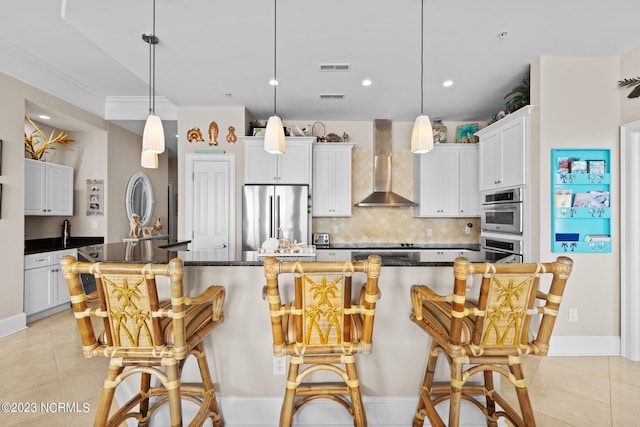 kitchen featuring appliances with stainless steel finishes, light tile floors, a center island with sink, wall chimney exhaust hood, and white cabinets