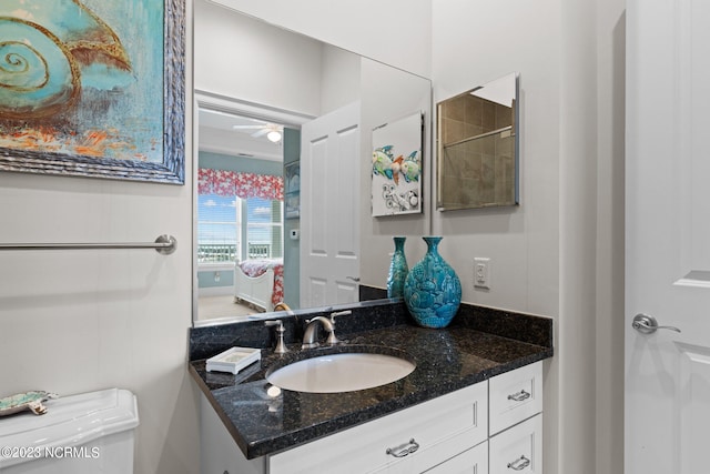 bathroom featuring ceiling fan, toilet, and vanity with extensive cabinet space