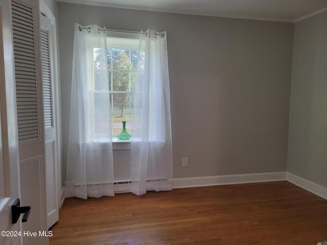 spare room featuring ornamental molding, a baseboard radiator, and hardwood / wood-style flooring