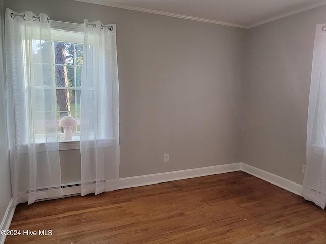 spare room featuring hardwood / wood-style floors, a baseboard heating unit, and ornamental molding