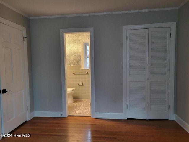 unfurnished bedroom with dark hardwood / wood-style floors, ensuite bath, a closet, and ornamental molding