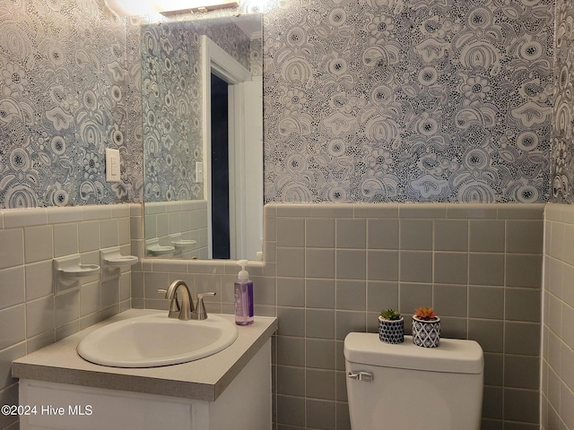 bathroom with vanity, tile walls, and toilet