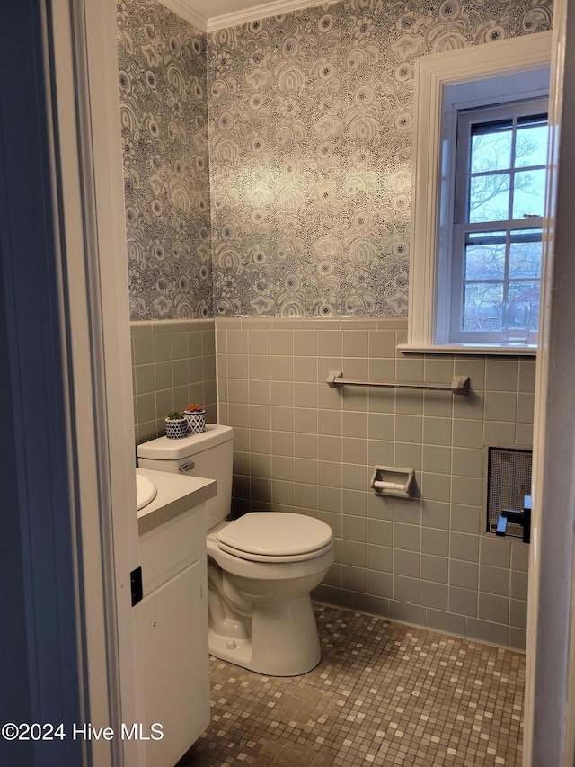 bathroom with vanity, crown molding, tile patterned flooring, toilet, and tile walls