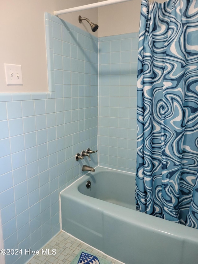 bathroom with tile patterned floors, tile walls, and shower / tub combo with curtain