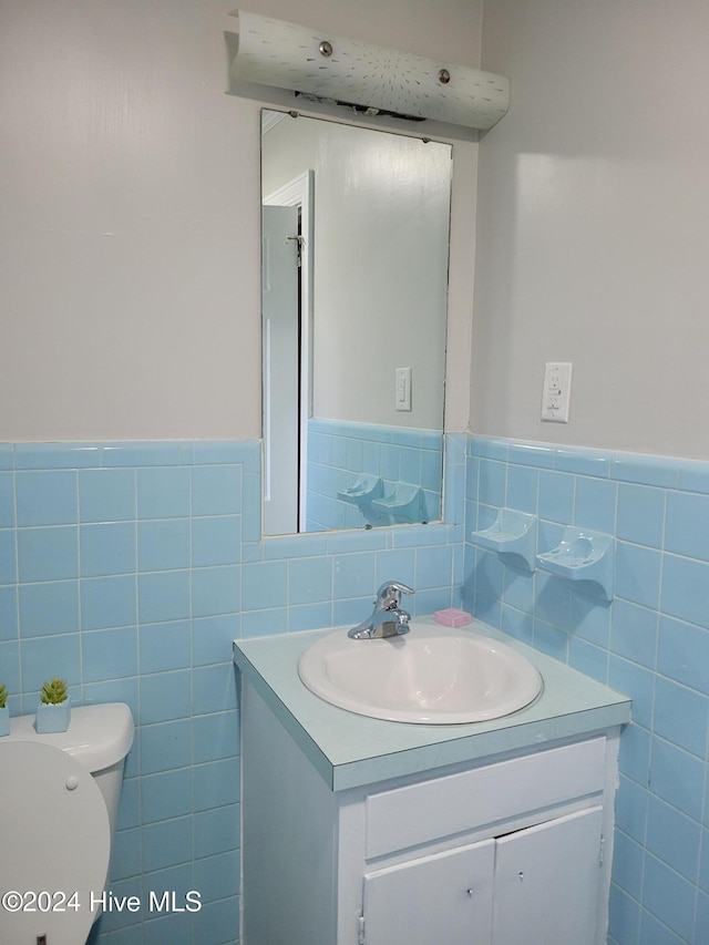 bathroom featuring vanity, toilet, and tile walls