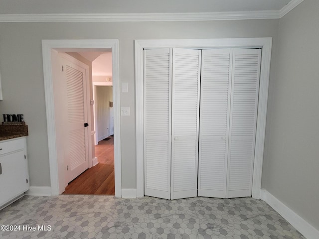 unfurnished bedroom with a closet, light tile patterned flooring, and ornamental molding